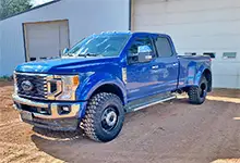 Blue pickup truck with Founders tires parked at shop