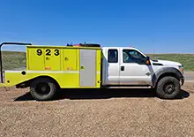 Yellow brush truck with Founders tires on grass